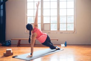 Lifestyle photo of young female in gym doing side plank